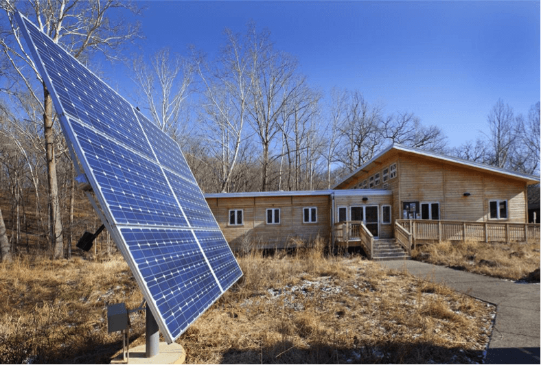 Solar panels in front of the wooden office, lab, and classroom building at the Tyson Research Center, one of the first buildings in the world to achieve Living Building Challenge certification.