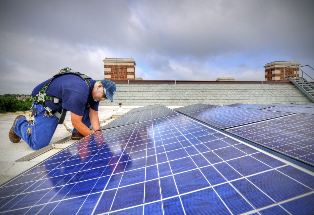 July 22, 2013 - Kevin Denzl works on solar panels on the roof of Brauer Hall. Photos by James Byard